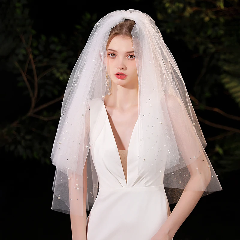 

A white elegant bridal veil adorned with simulated pearls, suitable for waist length veils at women's weddings