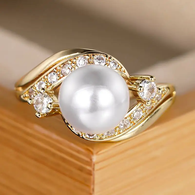 Huitan Eleganter Goldfarbener Damenring mit Imitationsperle, luxuriöses Party-Accessoire, geschwungenes Design, eingelegter glänzender CZ-Modeschmuck