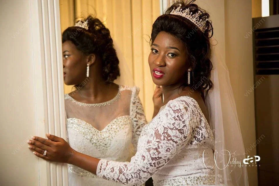 Suknie ślubne z koronką, dekoltem w łódkę, długimi rękawami, odpinanym trenem i odkrytymi plecami, zdobione uroczy, personalizowane kryształki.