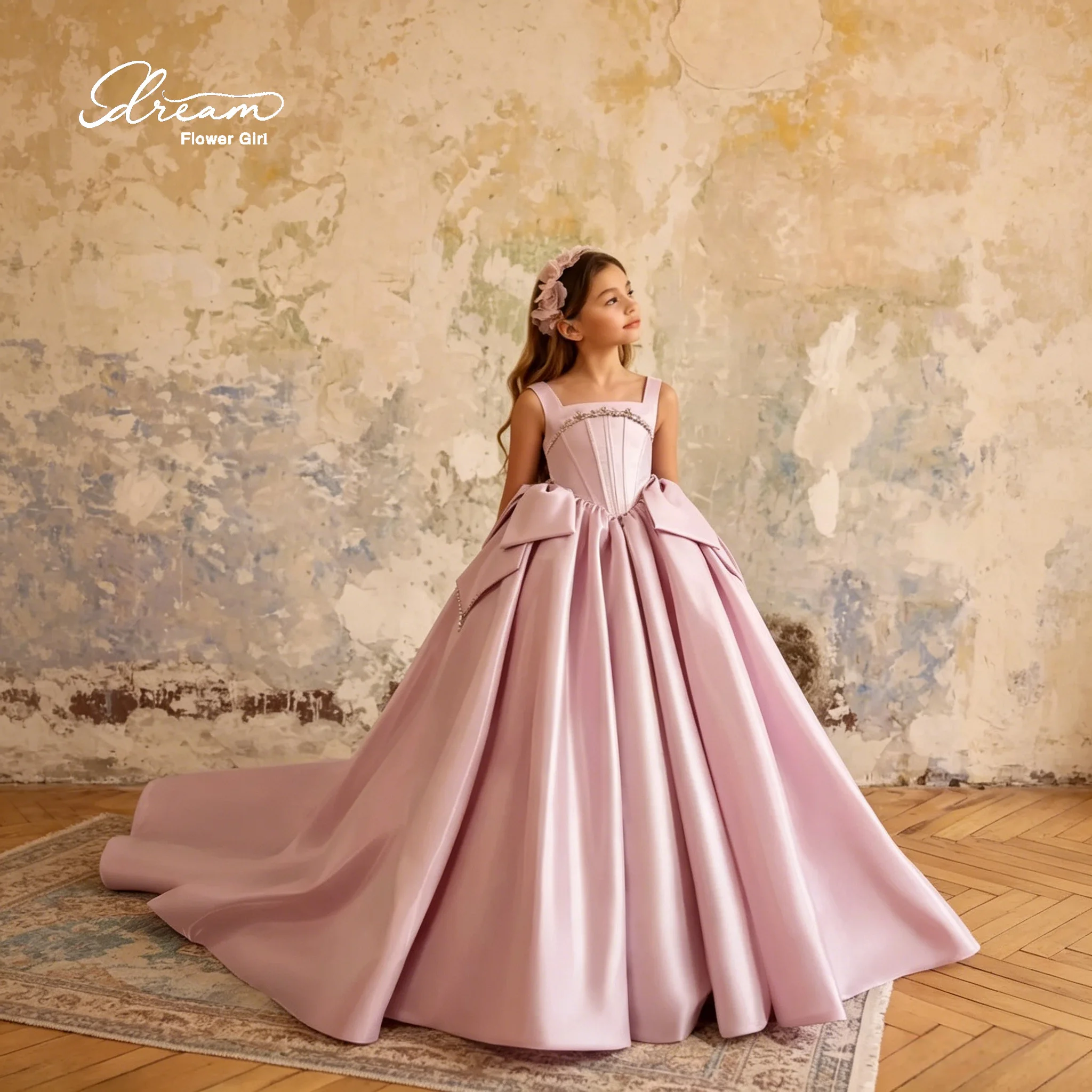 Classic and elegant pink sleeveless halter dress with floor-length bow and diamond embellishments for a ballroom event.