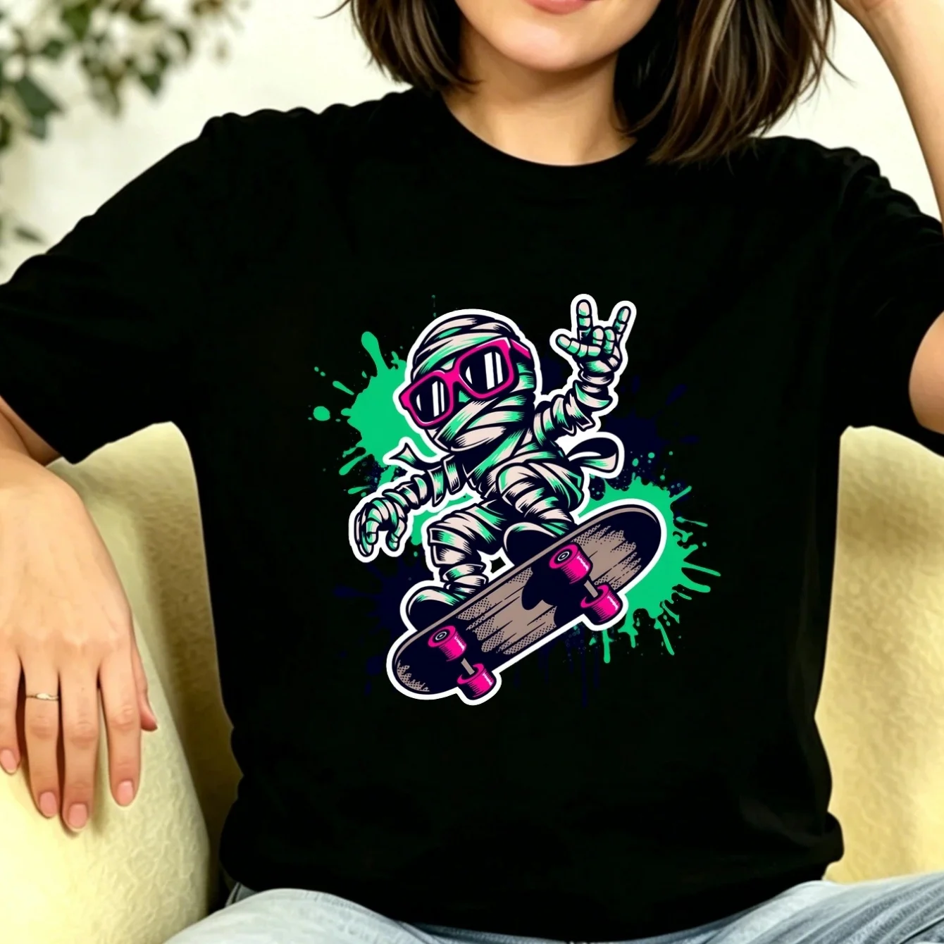 Camiseta negra estampada para mujer con diseño de momia genial montando en un monopatín, gafas de sol rosas y gesto de mano rockero