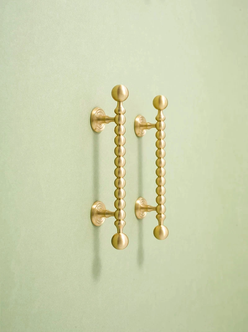 Pair of vertical beaded brass handles on green doors