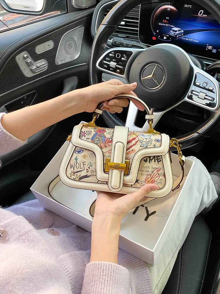 

Роскошная и популярная сумка-седло с милым граффити-принтом в виде медведя и высококачественной кожей, новая модная женская сумка через плечо 2026 года