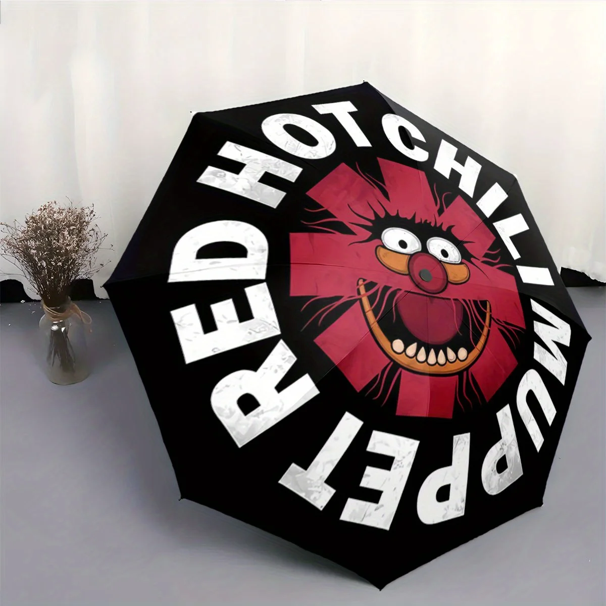 

Automatic Folding Umbrella A cartoon face over a red star with "Red Hot Chili Muppet" text. Portable collapsible design, casua