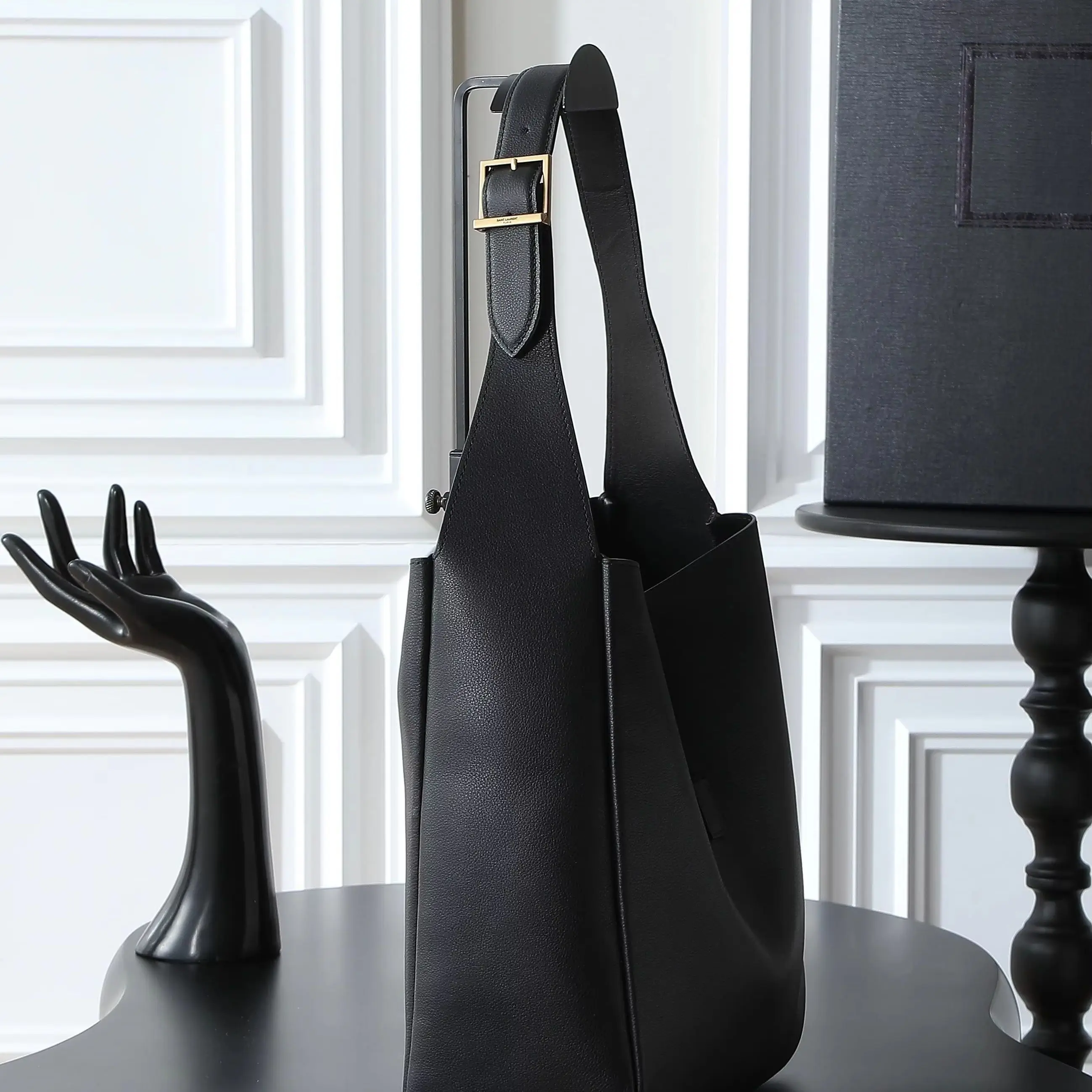 

Minimalist black pebbled leather bucket bag with an adjustable wide shoulder strap and a leather snap closure.