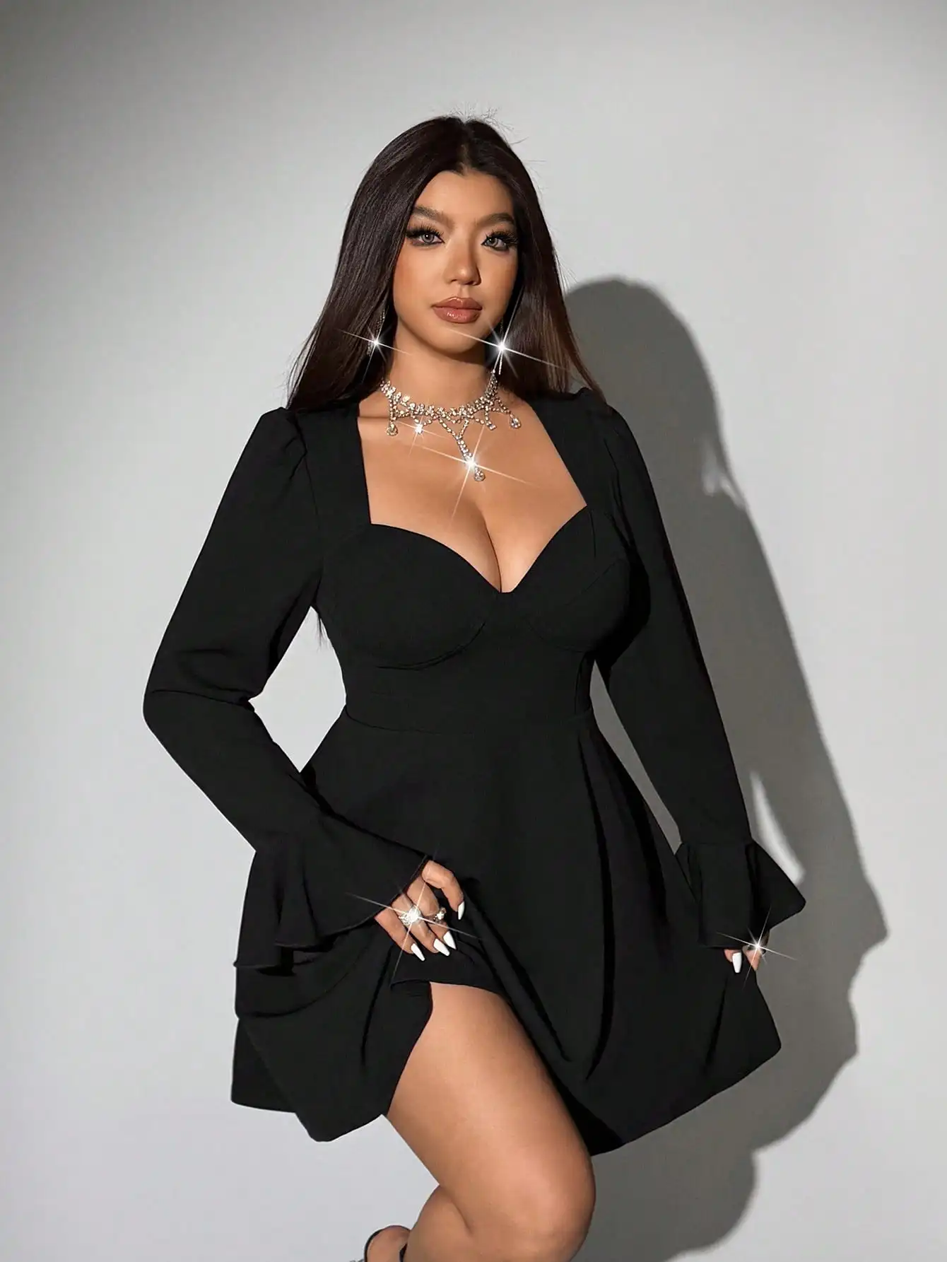 

Черное мини-платье А-силуэта с вырезом «сердечко», длинными рукавами, расклешенными манжетами и эластичной талией