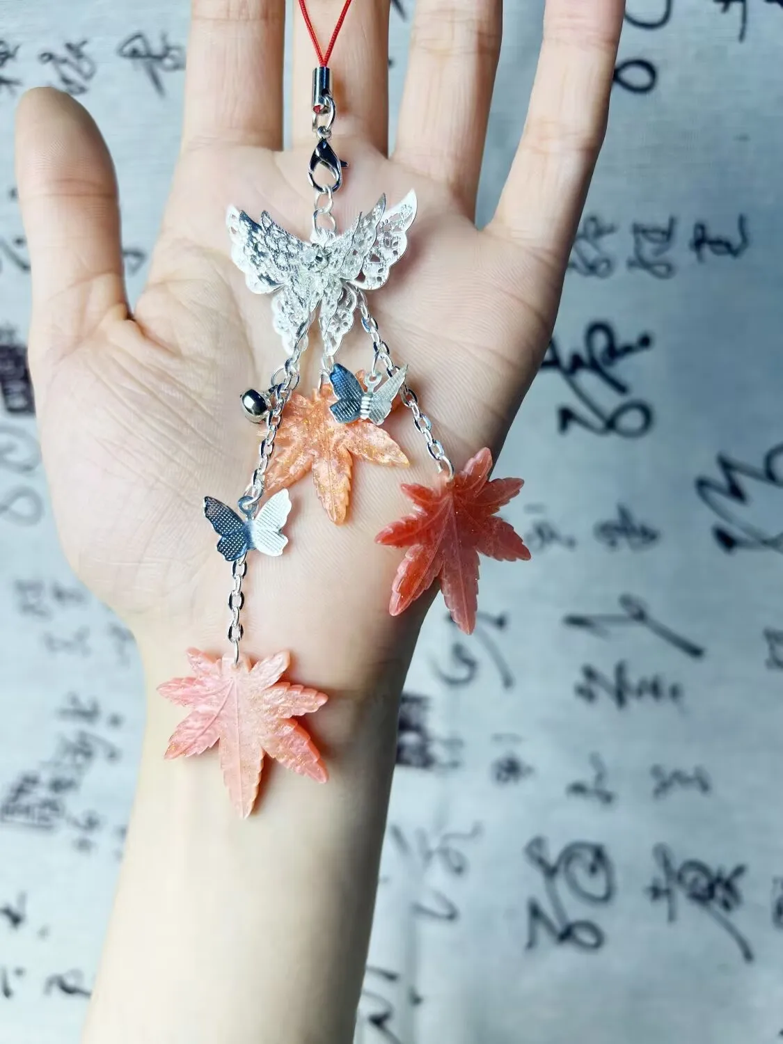 เทพธิดาสวรรค์ทรงพระราชากรุณาบุญคุณให้กับชาวเมืองดอกไม้ เซียเหลียน ด้วยเครื่องประดับรูปใบเมเปิ้ล กระดิ่ง และผีเสื้อสำหรับติดโทรศัพท์มือถือ