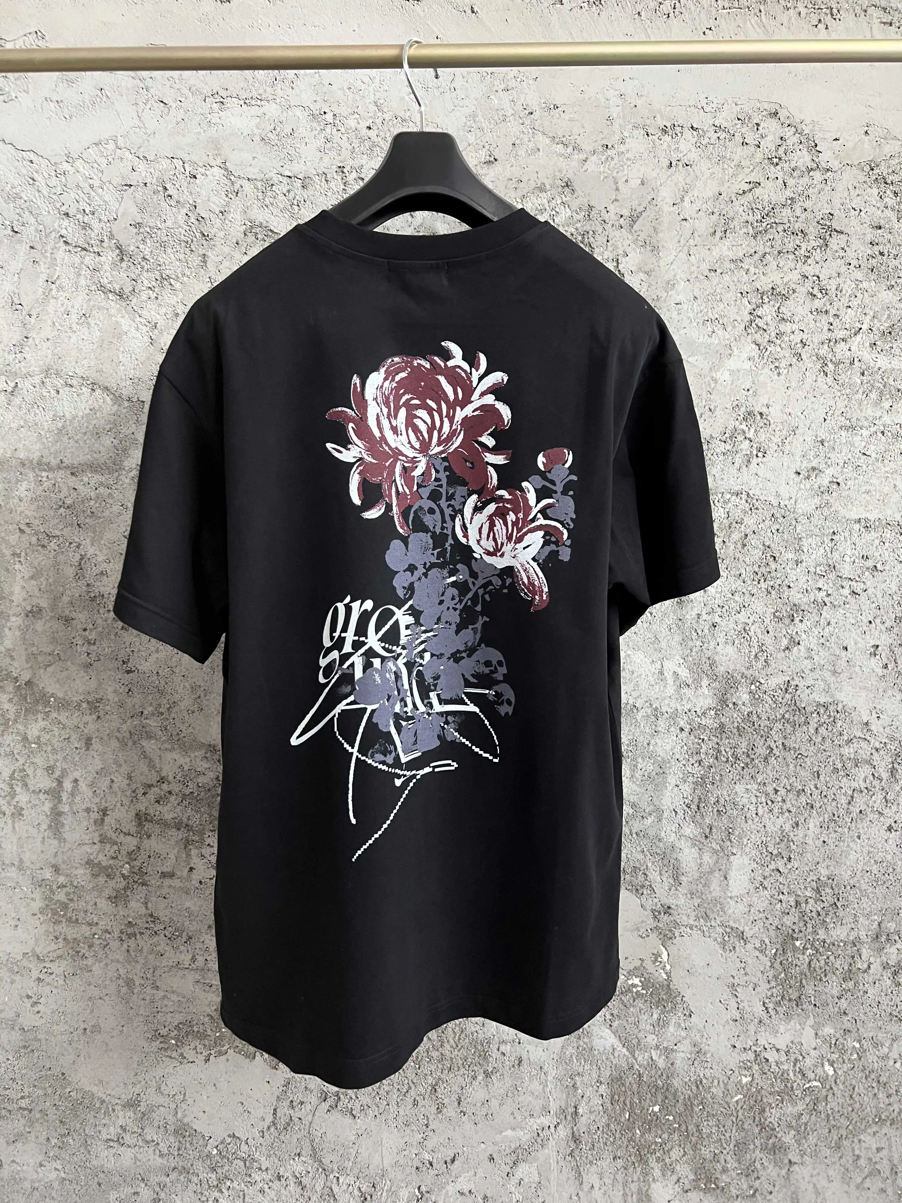 

A black T-shirt with a printed round neck and a floral pattern on the back