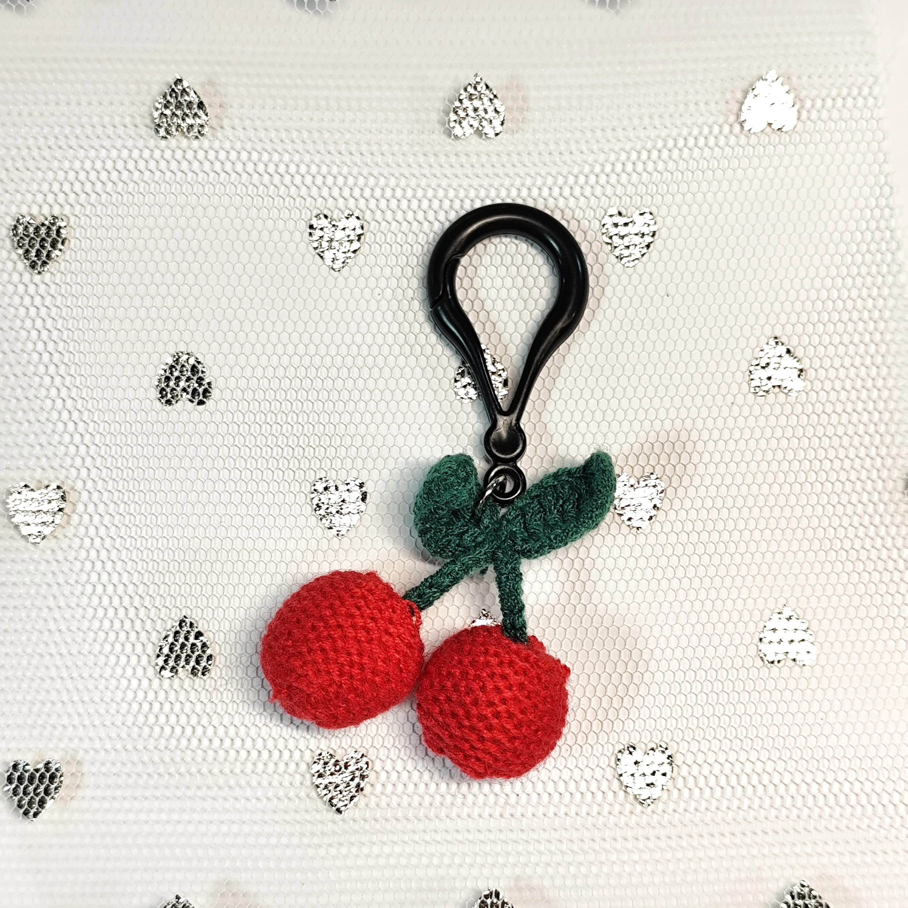 This handmade crochet cherry keychain, with vivid red cherries and green stems, is a cute accessory.