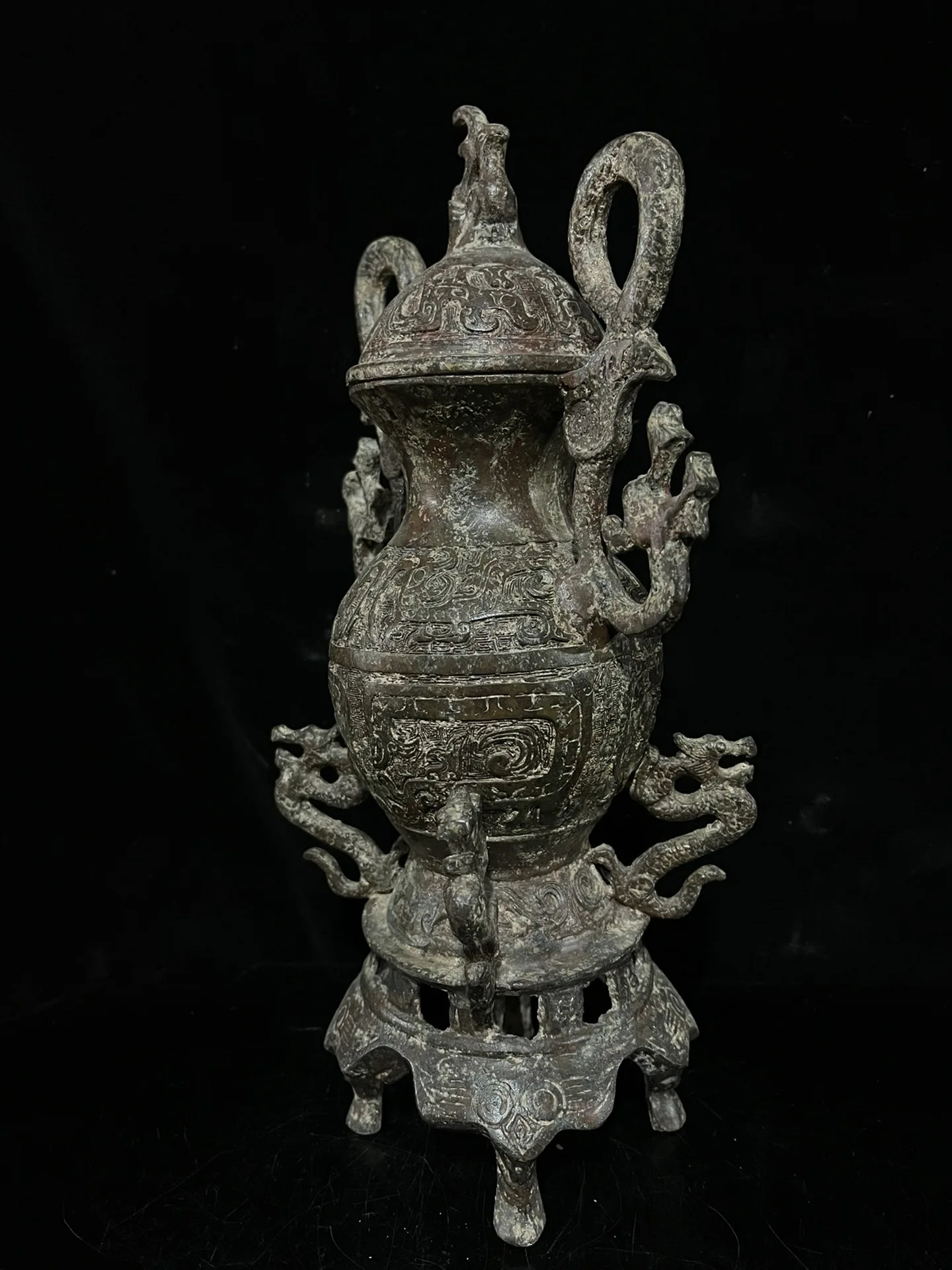 Old bronze vessel featuring red and green patina, adorned with twin dragon motifs.