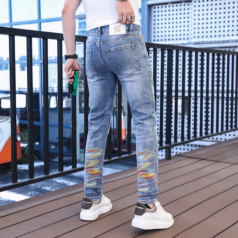 Celana panjang ketat pergelangan kaki pria, Jeans cetakan warna Mode desain kepribadian jalanan trendi Punk tampan meregang Slim Fit