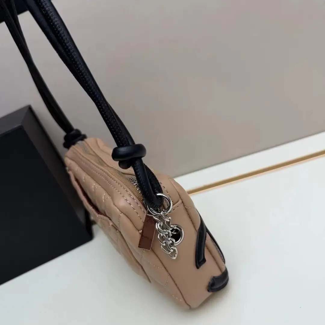 Bolso acolchado bicolor beige y negro con correa de cuero anudada y mini bandolera con cremallera.
