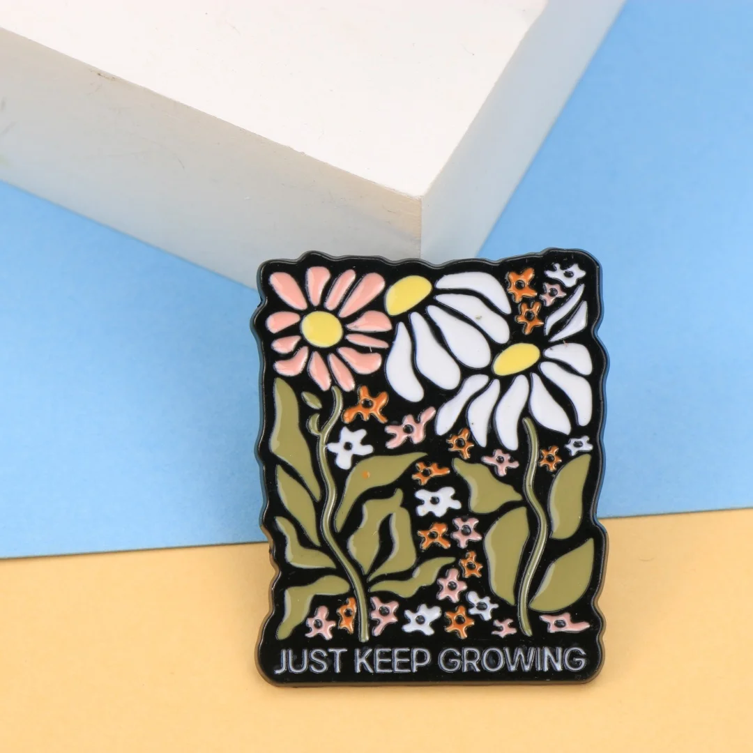 Épinglette en émail florale « Just Keep Growing », broche avec citation inspirante, fleurs pastel et fond noir, affirmation positive