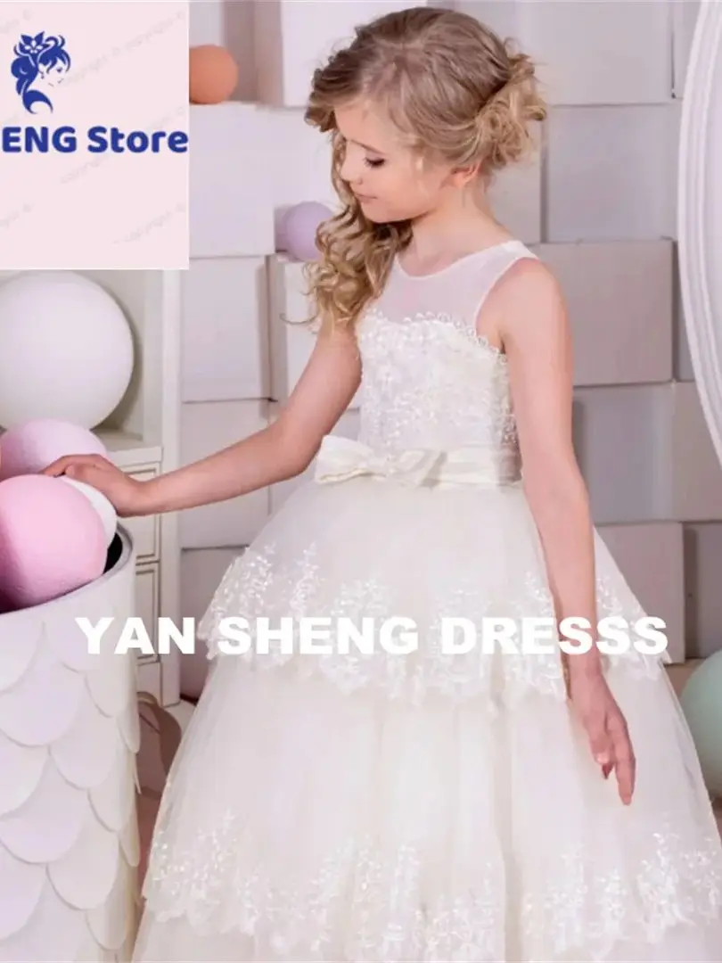 فساتين فتاة الزهور المخصصة من التل العاجي والتطريز بالدانتيل مع حزام فيونكة بدون أكمام لحفلات الزفاف وأعياد الميلاد والتواصل المقدس