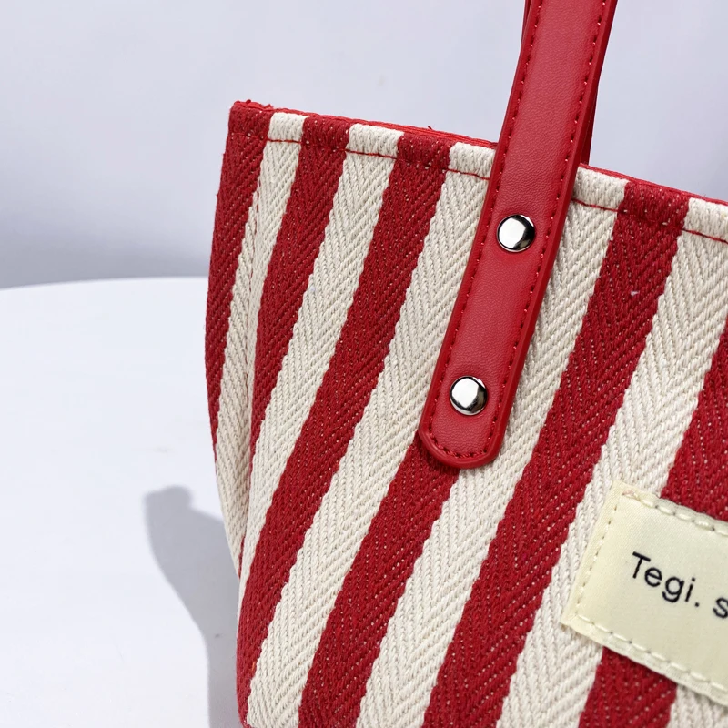 Bolsos de lona a rayas de estilo japonés para mujer bolsos y monederos de diseñador de lujo novedad de 2024 en letras decoración de colores contrastantes bolso de hombro pequeño de tela para las axilas alta calidad