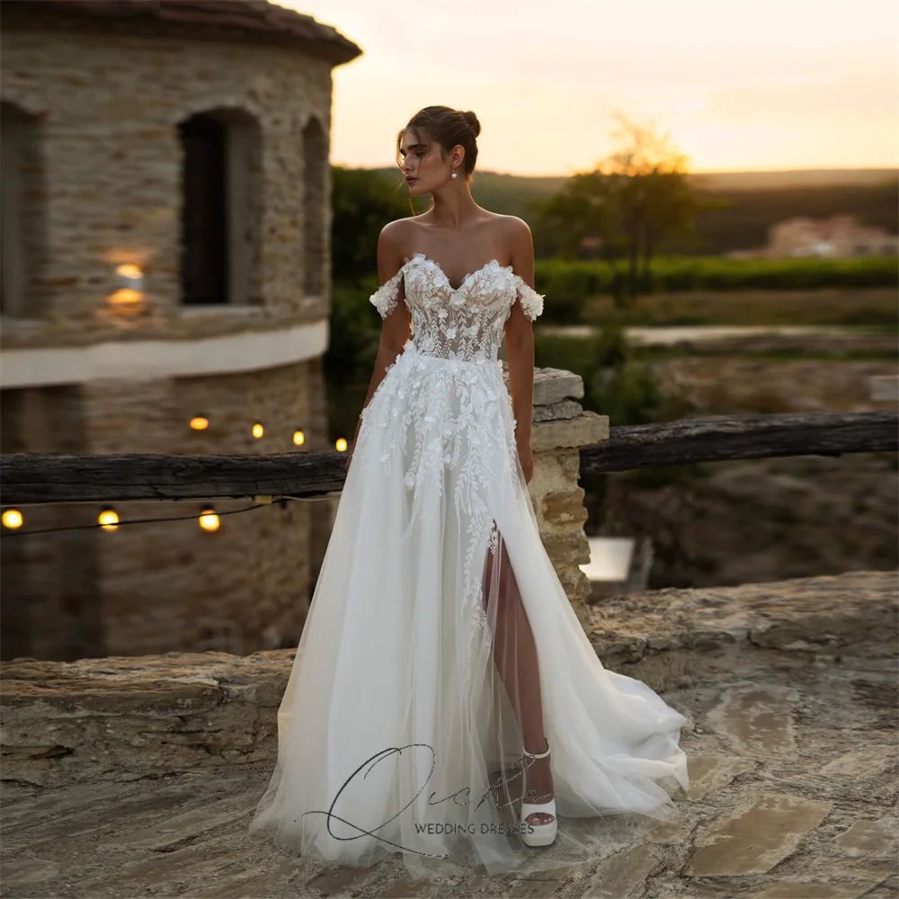 Elegancka suknia ślubna QICHE z aplikacjami z koronki, dekoltem w serek, krojem A-line, tiulowa, z odkrytymi ramionami, kwiatami 3D, rozcięciem, tiulowym odkrytym tyłem, możliwość personalizacji, kolekcja 2026.