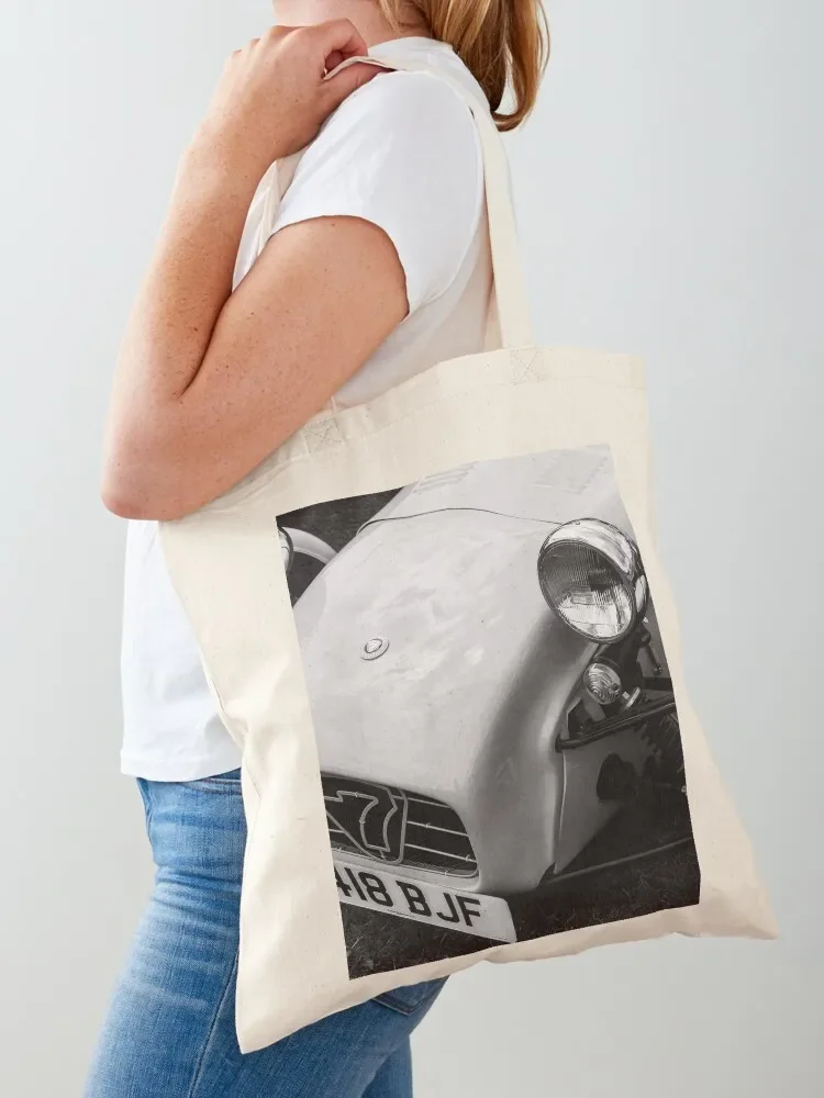 A black and white image of the front of a 1996 Caterham Super 7 on display at a car show Tote Bag shopping cart bags Tote Bag