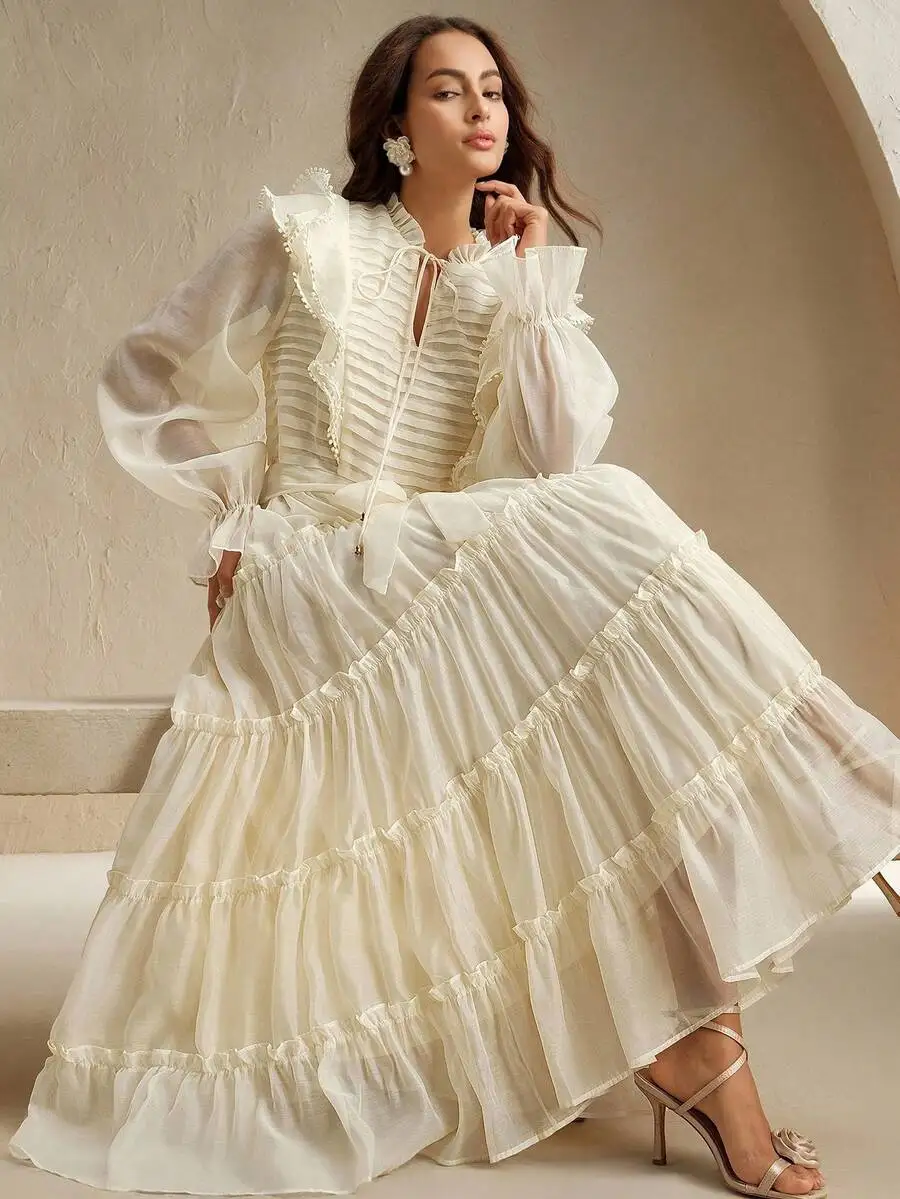 

Элегантное многослойное платье цвета слоновой кости с рюшами по подолу, пышными рукавами и кружевной отделкой