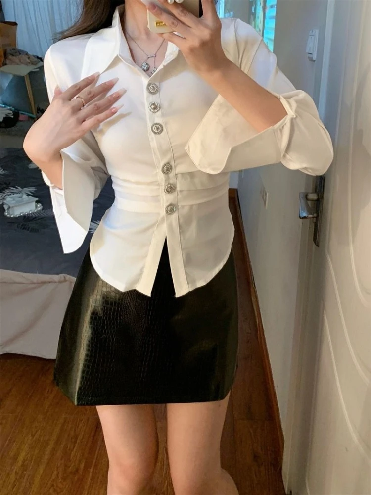 Elegancka damska bluzka z nieregularnym podkreśleniem talii, długim rękawem, z miękkiego, połyskującego materiału, jesienna moda, biała, casualowa, szykowna góra. ​