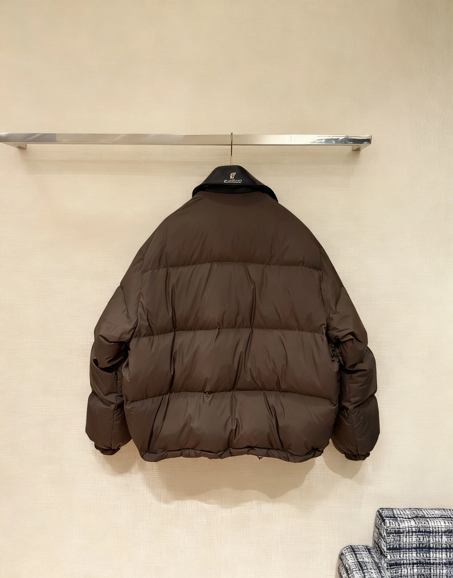 Damska kurtka puchowa w kolorze ciemnego brązu z kołnierzem ze skóry, pikowana, ciepła, z regulowanym pasem, odzież wierzchnia na zimę 2025.