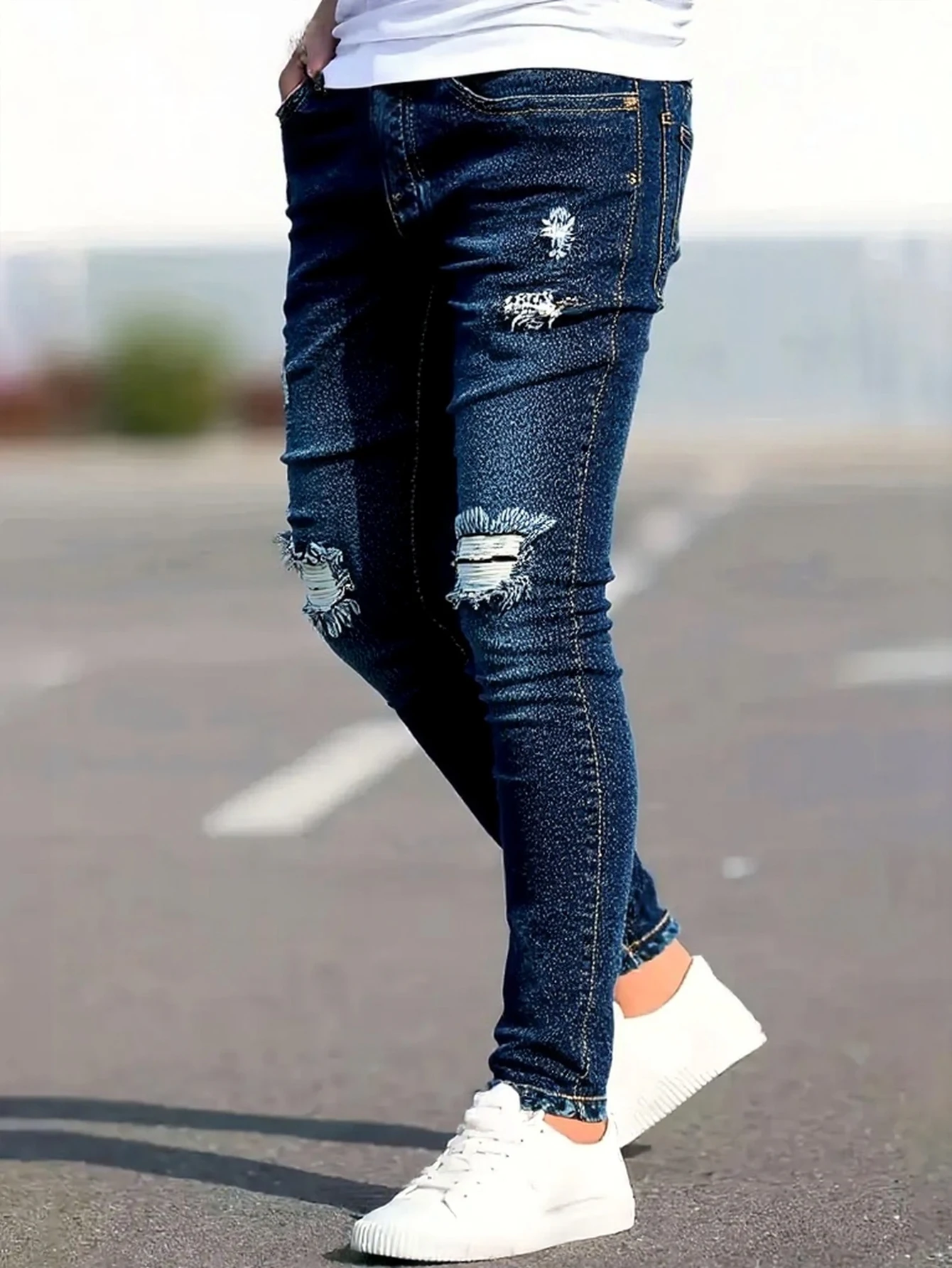 メンズのブルーのダメージ加工スキニージーンズ。膝やその他の部分にヴィンテージ風のリップ加工が施され、体にぴったりフィットするデザインです。