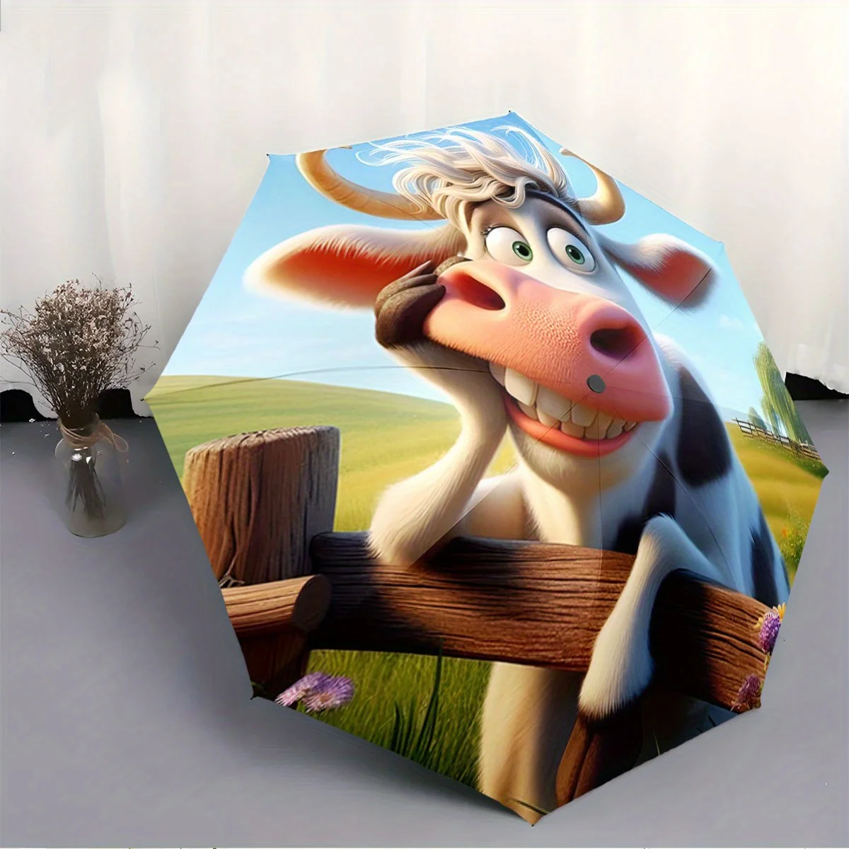 

Складной зонт. На зонтике изображена улыбающаяся корова, прислонившаяся к деревянному забору, на фоне живописного сельского пейзажа.