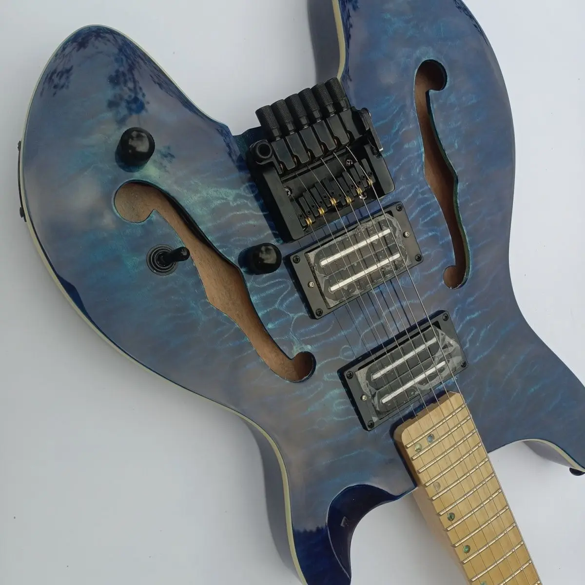 Double F-hole blue large patterned fan-shaped headless electric guitar, Korean made pickup bridge, mid-range electric guitar