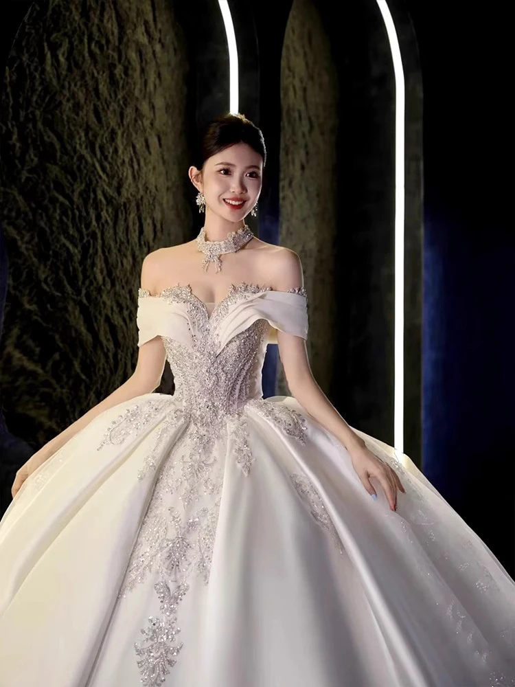 ชุดแต่งงานผ้าซาตินแบบไหล่เดียว ประดับตกแต่งอย่างหรูหรา พร้อมชายกระโปรงยาวแบบสเวปเทรน  ลายมัดย้อมแบบราชวงศ์  ประดับเพชรอะคริลิก  งานปักลายกลางตัวชุด