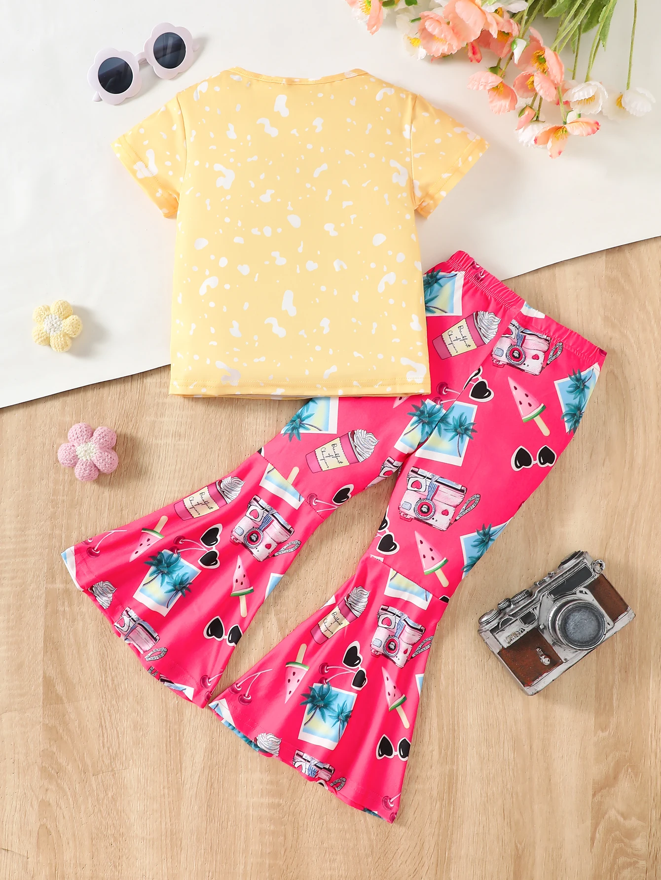 A two-piece summer set for girls consists of a T-shirt with cartoon cat prints and animated flared pants. Made of comfortable po