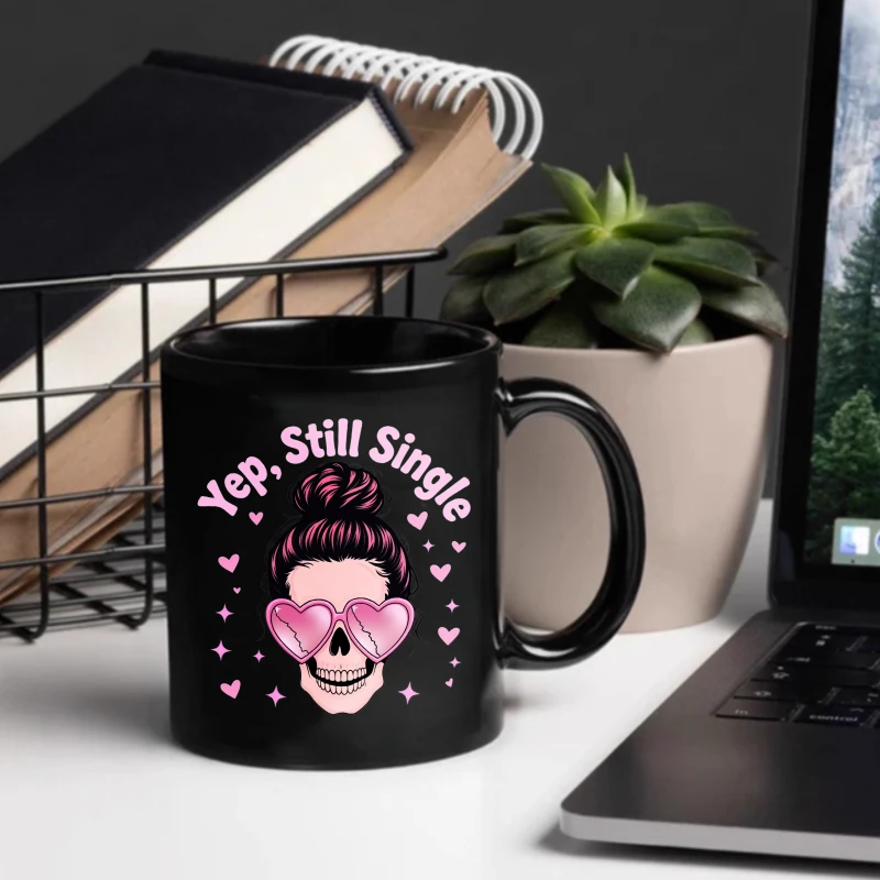 A black ceramic mug with a pink skull and heart-shaped sunglasses design emblazoned with the words 