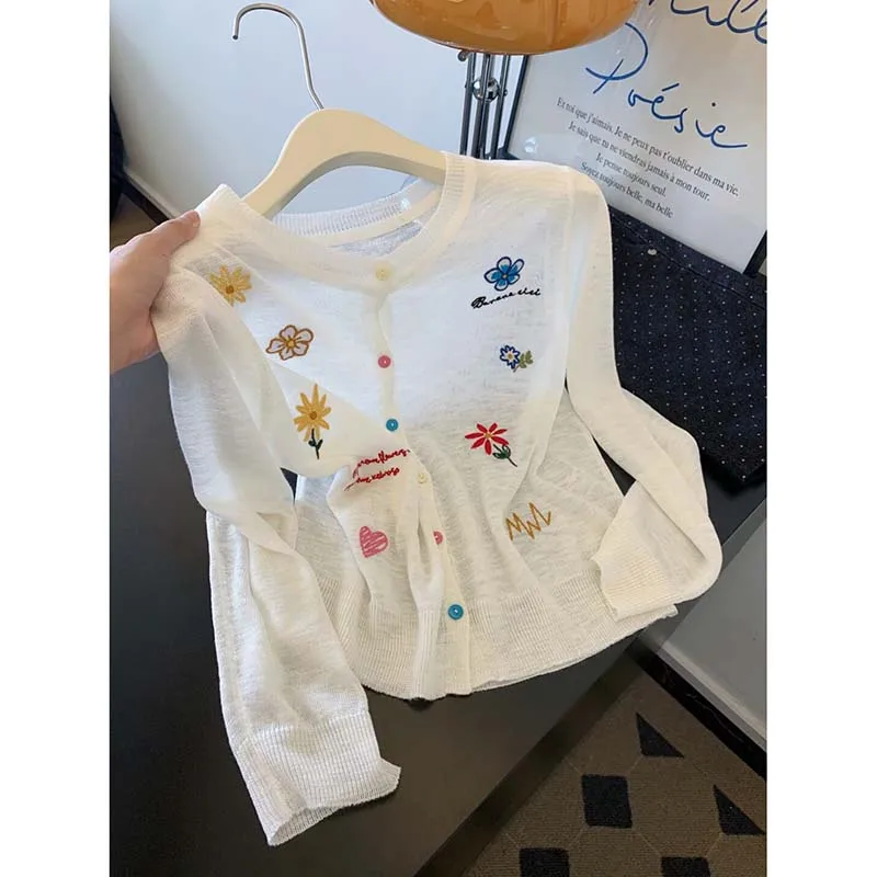 

White embroidered sun-proof knitted cardigan women's summer thin 2026 new air-conditioned blouse with short blouse.
