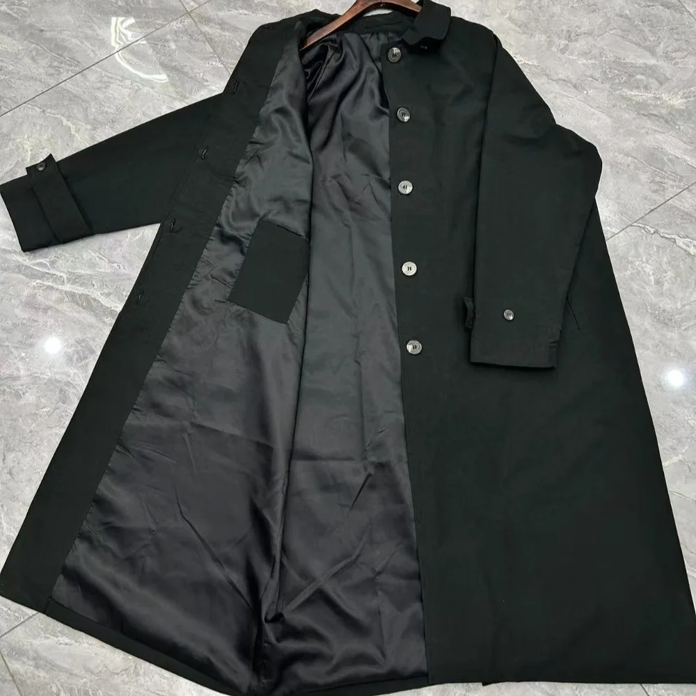 Jesienny płaszcz wiatrówka o klasycznym kroju, z wysokim rozcięciem, wykonany z mieszanki bawełny, o kroju litery A, średniej długości, zapinany na wiele guzików.