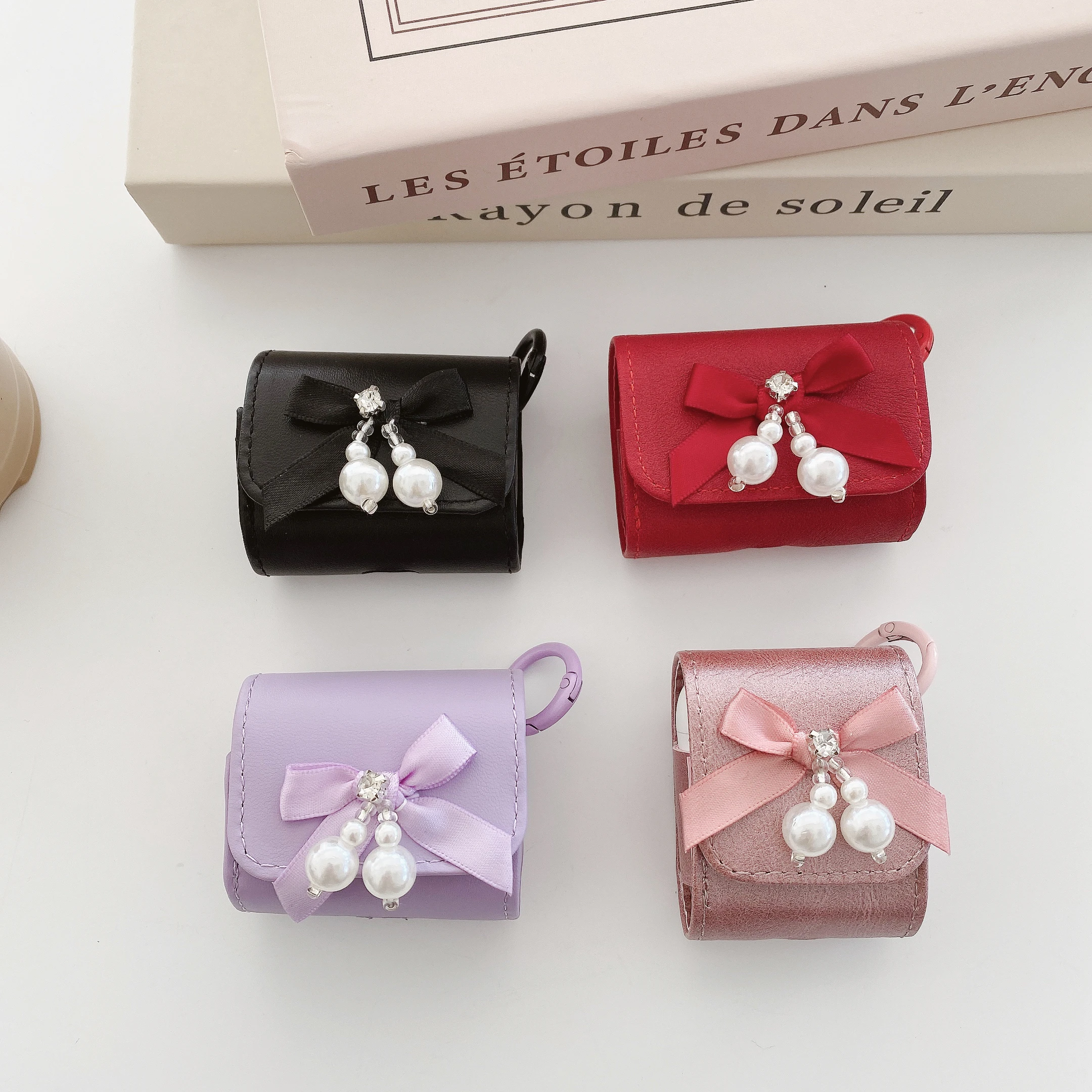 حافظة سماعات عصرية فاخرة من جلد البولي يوريثان مع عقدة على شكل فيونكة لؤلؤية كريستالية باللون الأسود والأحمر مع خطاف لأجهزة AirPods 1 2 3 4 Pro2 Pro 3