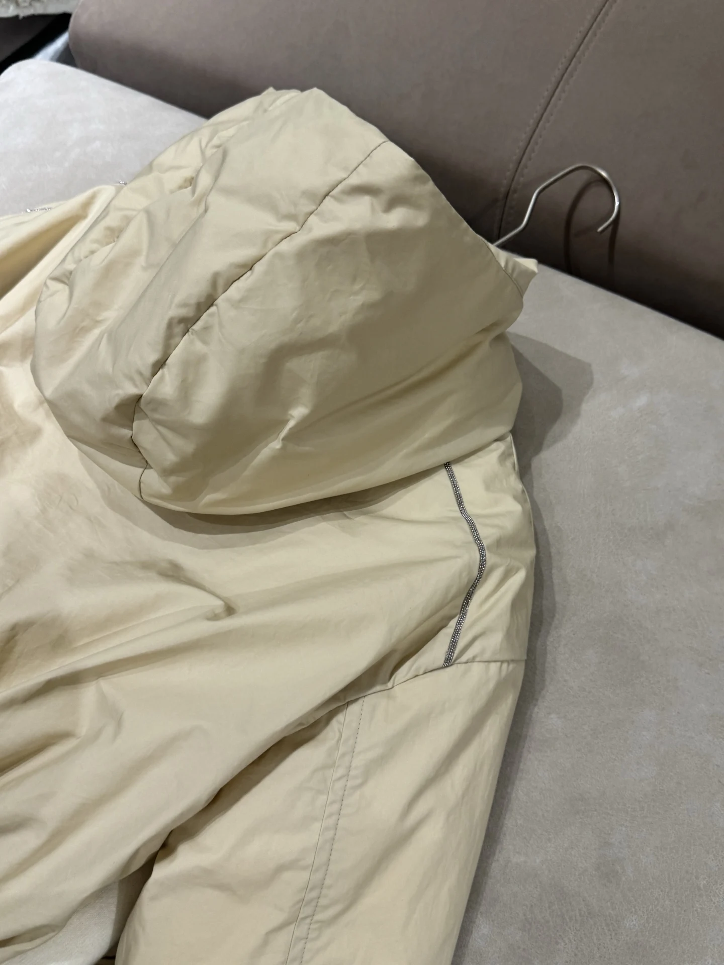 เสื้อแจ็คเก็ตขนเป็ดผสมแคชเมียร์ ขนสัตว์ และผ้าไหม พร้อมฮู้ด แต่งโซ่ประดับลูกปัด และแขนเสื้อแบบดรอปชอลเดอร์ เพื่อทรงสวยสง่า