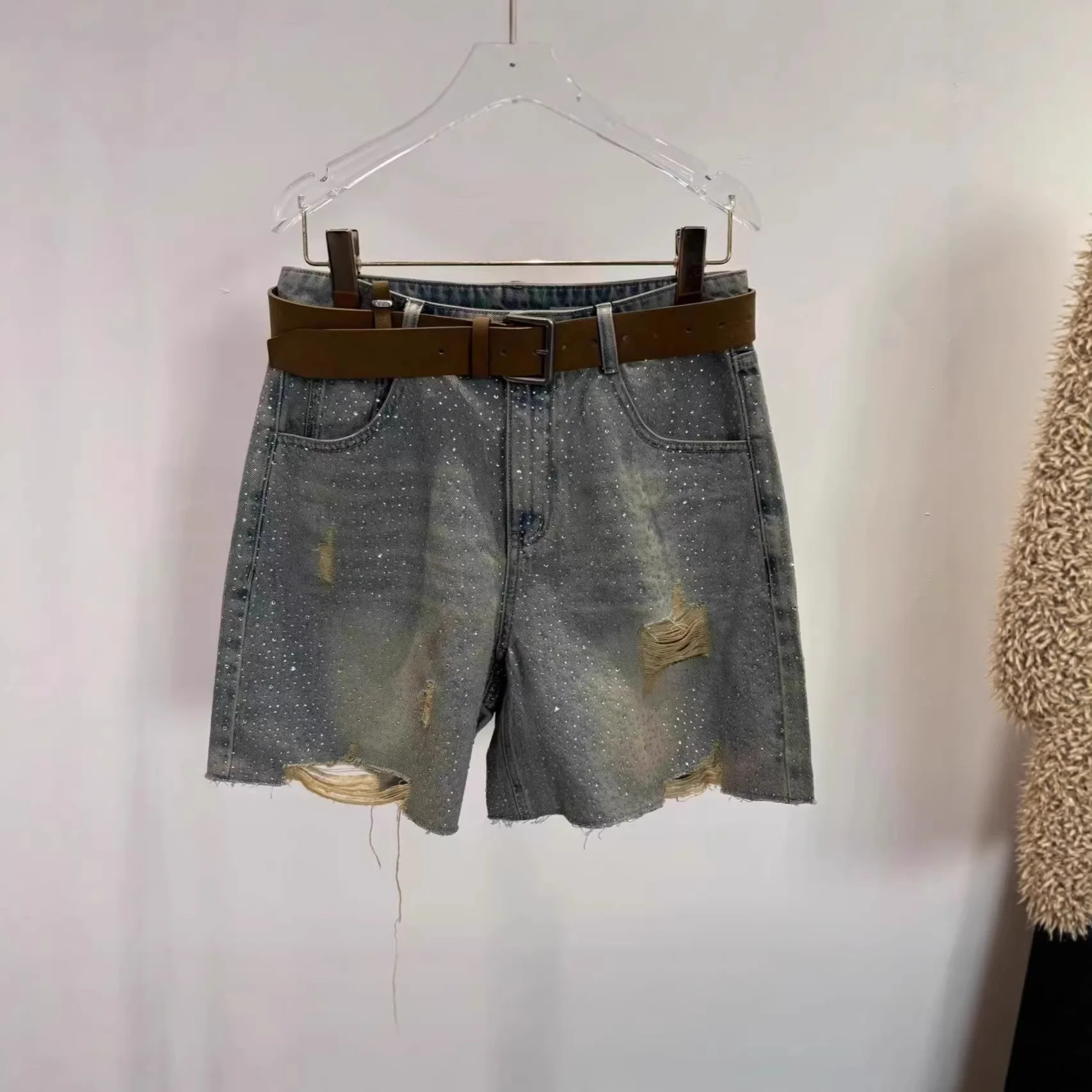 Retro distressed beaded denim shorts with high waist for slimming effect, paired with a belt and a five-pocket pants.