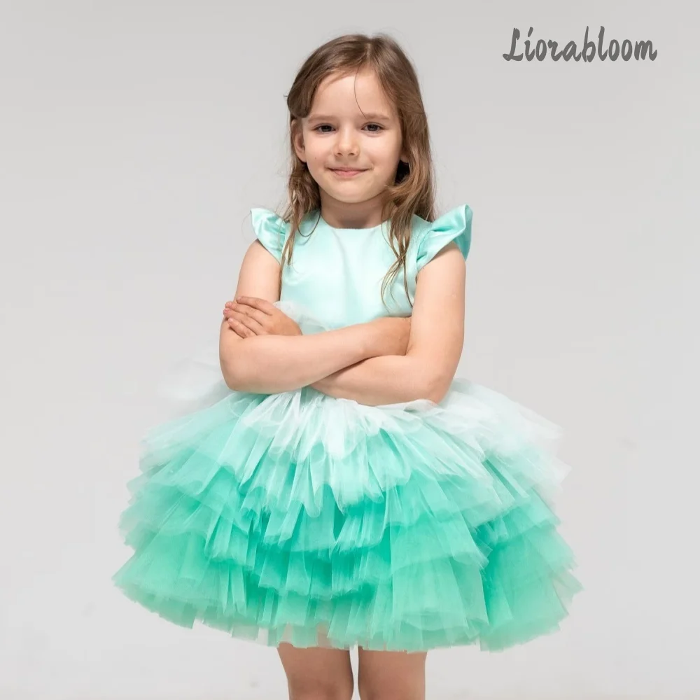 Abito da bambina verde smeraldo con gonna in tulle a balze e maniche con fiocco, ideale per spettacoli, matrimoni e damigelle.