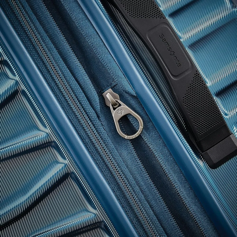 Расширяемый чемодан с твердой поверхностью и двойными вращающимися колесами. Эргономичная система тяги. Прочный корпус из поликарбоната. Надежные молнии для путешествий.