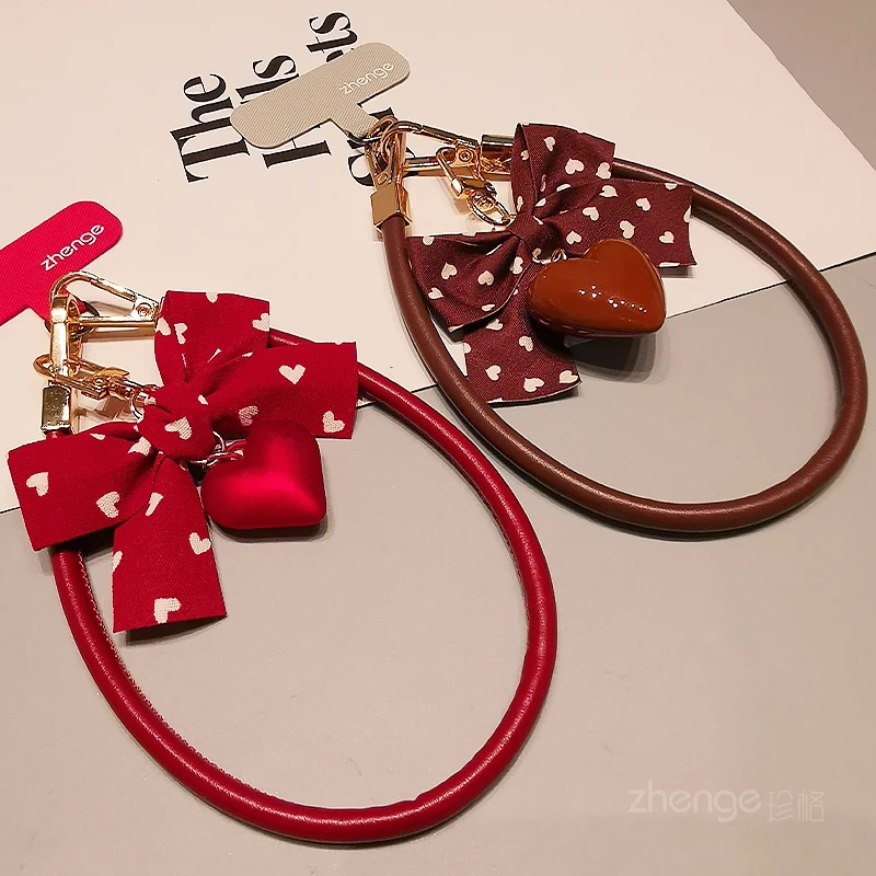 

‌ Новый женский кожаный ремешок для телефона 2026 года: с бантом и подвеской-сердцем, наручный ремешок от потери, универсальный для iPhone/Samsung