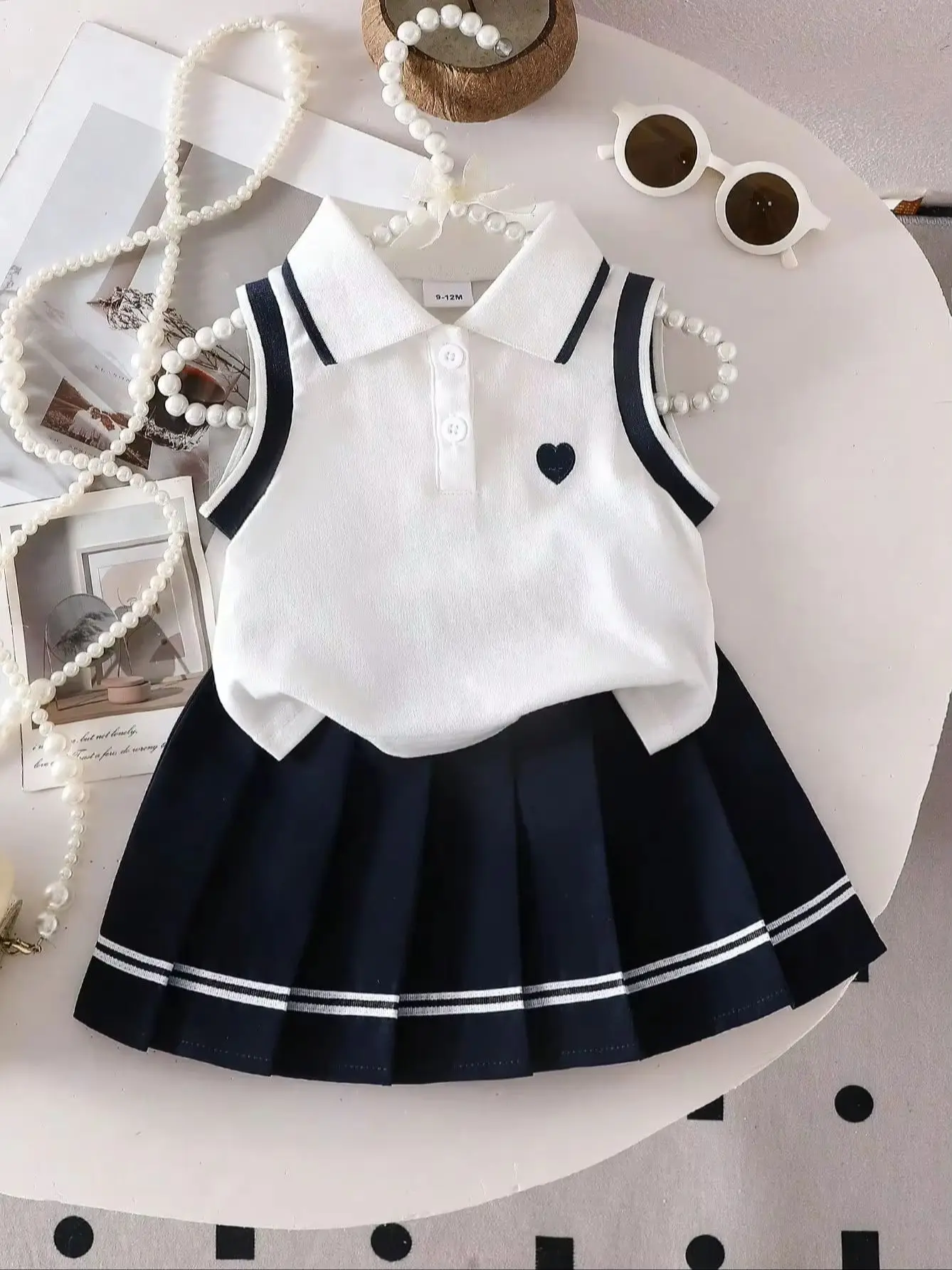 Zweiteiliges Set für Babys: ärmelloses Oberteil mit herzbesticktem POLO-Kragen und gewebter, lässiger, plissierter kurzer Rock im süßen und coolen Stil. – Detail 1