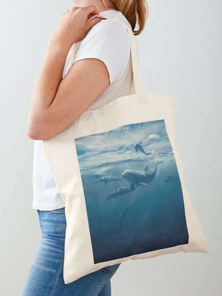 Swimming happy dolphins under a cloudy blue sky and a blue ocean Tote Bag Women's shopper bag Cloth bag shopper bags