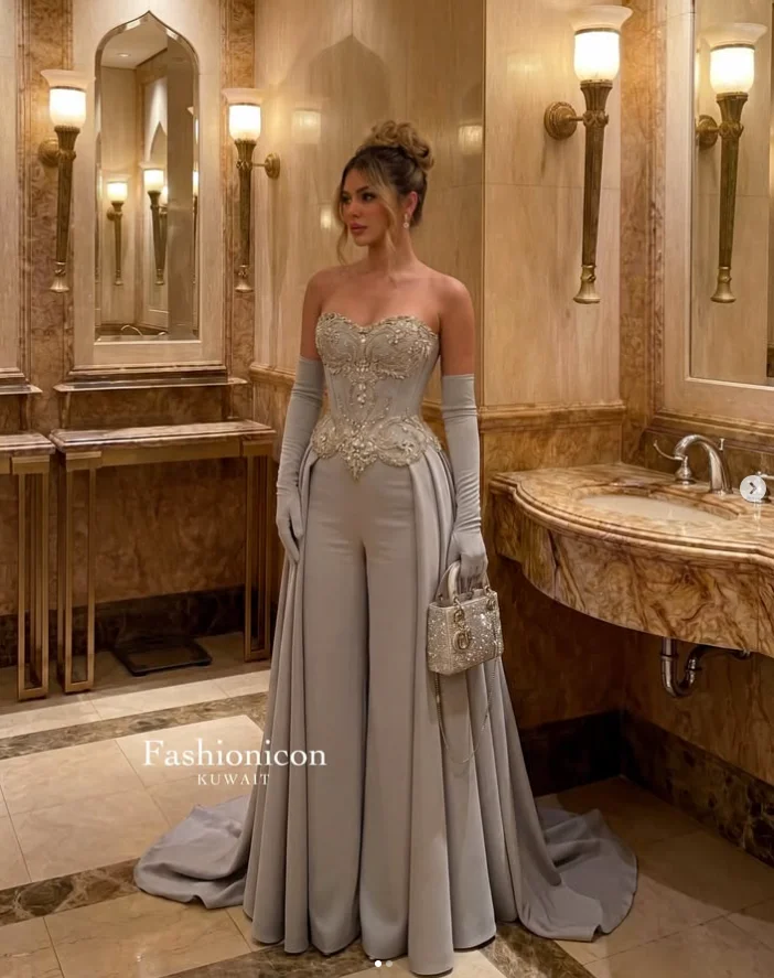 Silberner Luxus-Jumpsuit für besondere Anlässe mit Überrock, glitzernden Kristallen, herzförmigem Ausschnitt und seitlichen Einsätzen, maßgeschneidertes Abendkleid