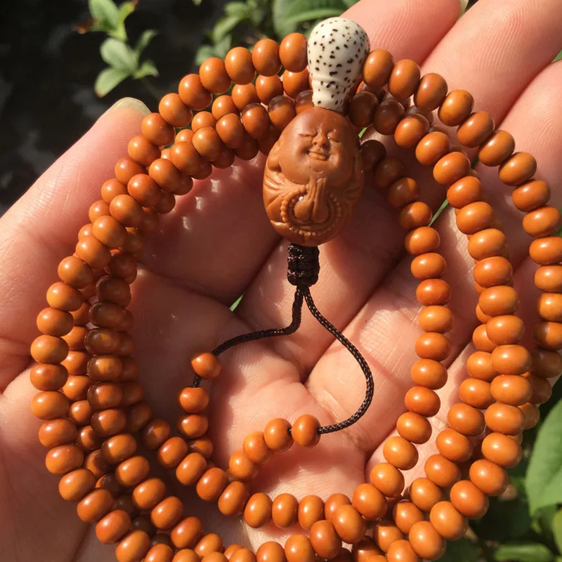 A - apple pendant necklace, paired with an olive-pit carving symbolizing devotion to Buddha.