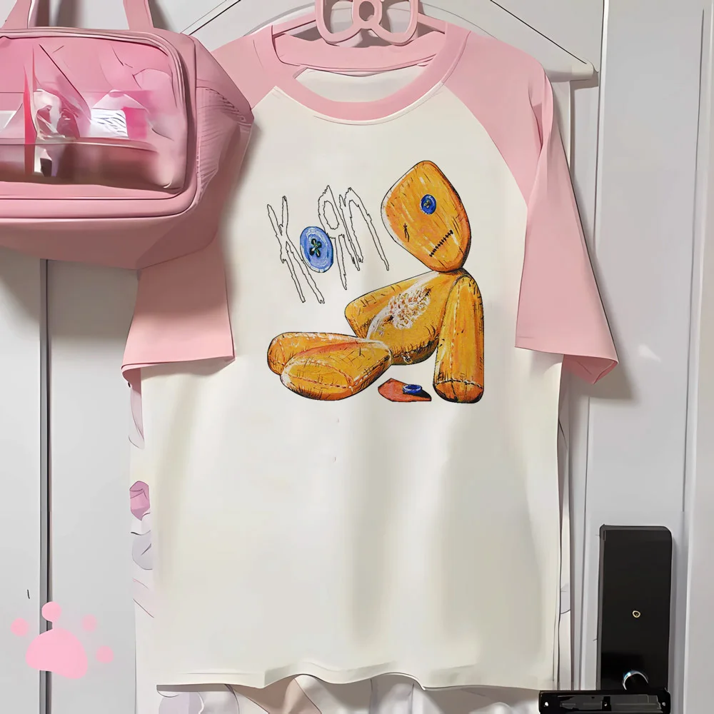 Camiseta raglán Korn: rosa y blanca con estampado de muñeco de trapo del álbum "Iconic Issues", ideal para fans del rock y conjuntos urbanos alternativos.