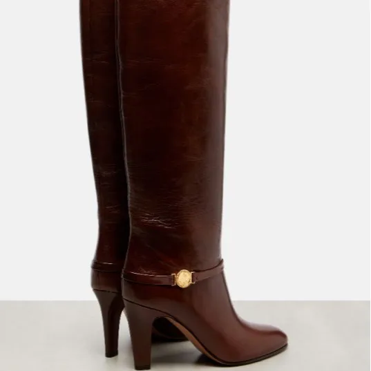 Women's Leather Knee-High Boots Gold Emblem Detail Stiletto Heel Sleek Elegant Design for Classic Casual Autumn Fashion Looks