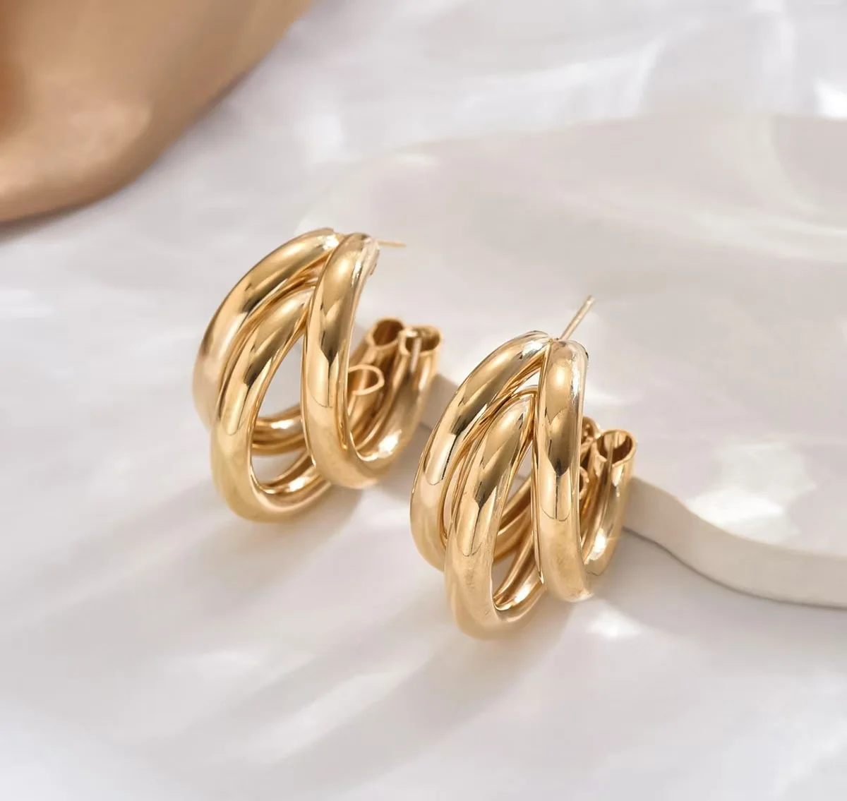 أقراط دائرية ذهبية للسيدات، مصنوعة من مادة معدنية، تتميز بتصميم هندسي أنيق وعجلي، مما يزيد عن كبيرة وفاخرة