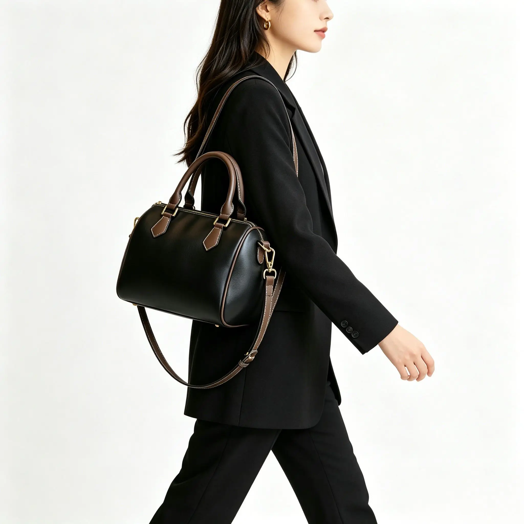 

Black and brown two-tone leather barrel bag with top handles, gold-tone hardware, and a detachable crossbody strap.