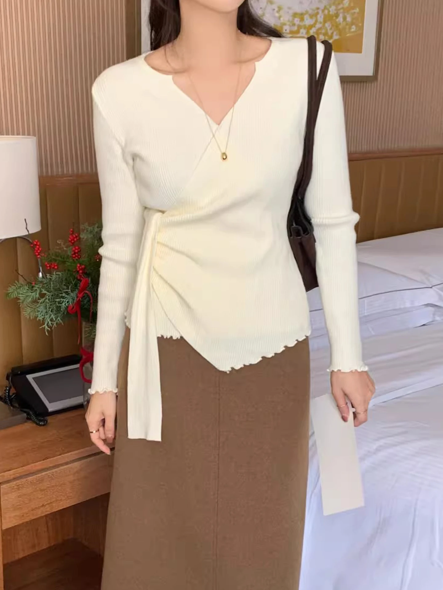 เสื้อสเวตเตอร์ถักคอวีไขว้สำหรับผู้หญิง ทรงเข้ารูป ใส่เป็นเสื้อตัวในได้ เหมาะสำหรับฤดูใบไม้ร่วงและฤดูหนาว เนื้อผ้านุ่มสบาย ดีไซน์ทันสมัย พร้อมดีเทลผูกโบว์ที่คอเสื้อ