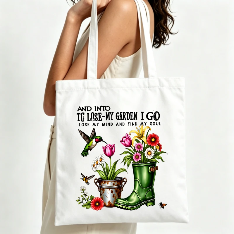 Women's garden-themed canvas tote bag with floral, hummingbird and boot graphics, perfect for daily gardening and casual outings