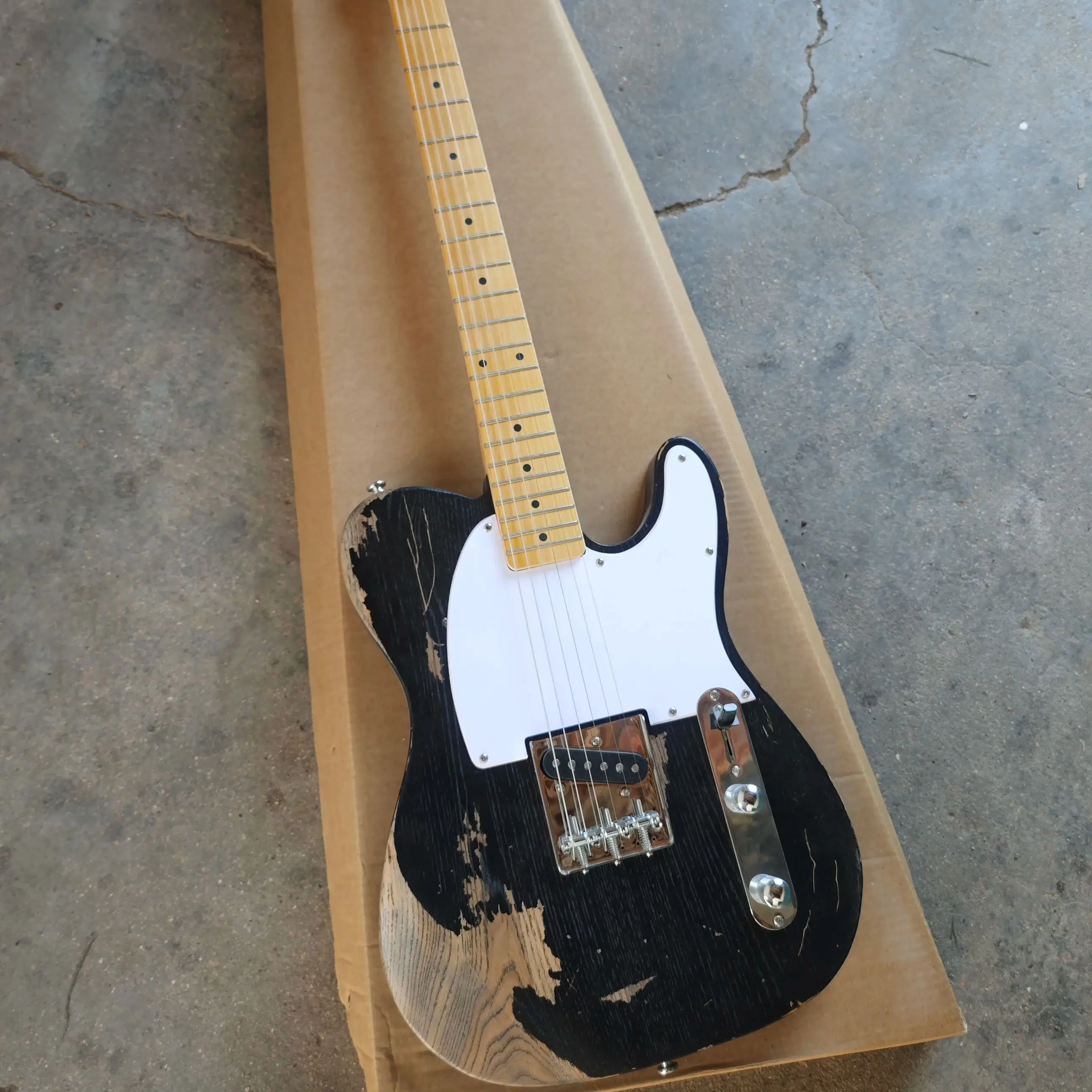 

Black six string electric guitar with distressed treatment, featuring a basswood body, maple neck, and white panel