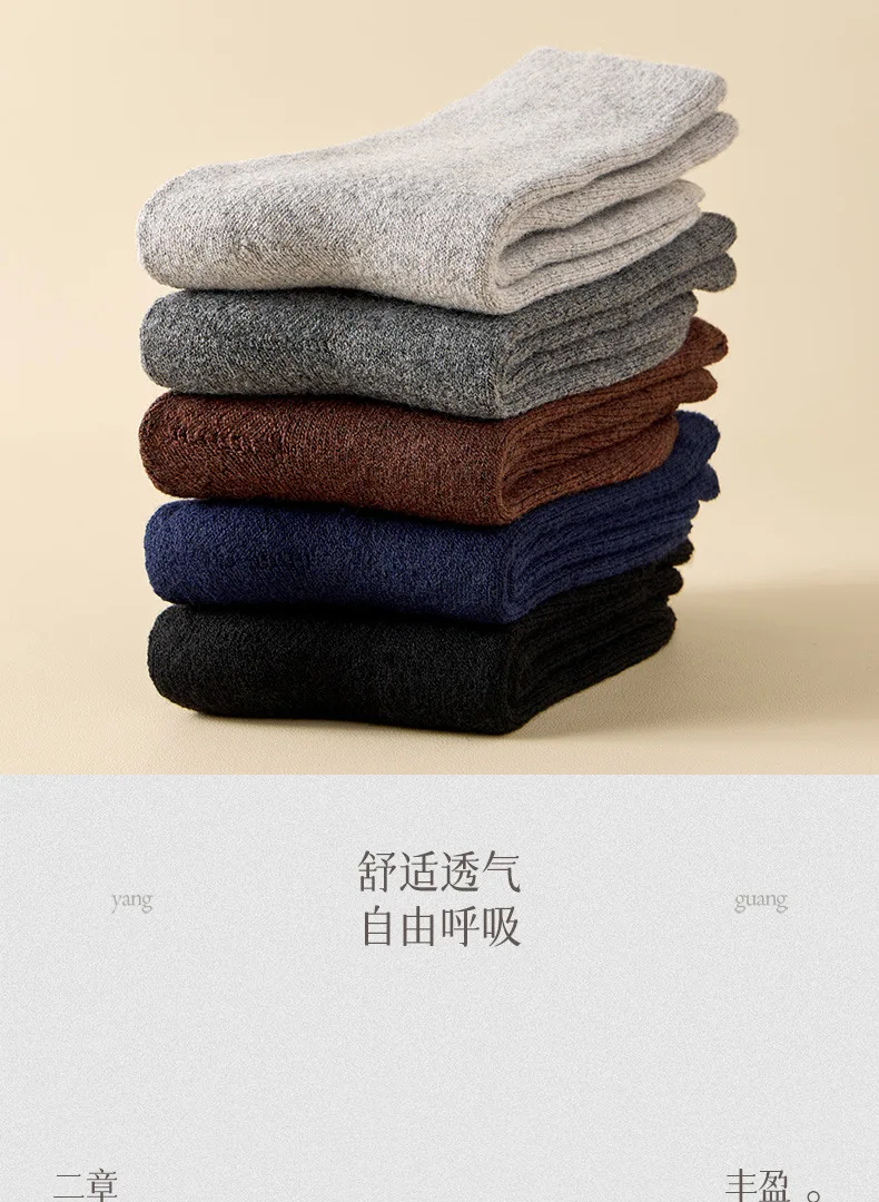 Una pila de cinco calcetines de lana de invierno doblados para hombres en tonos neutros, incluidos gris claro, gris oscuro, marrón, azul marino y negro.